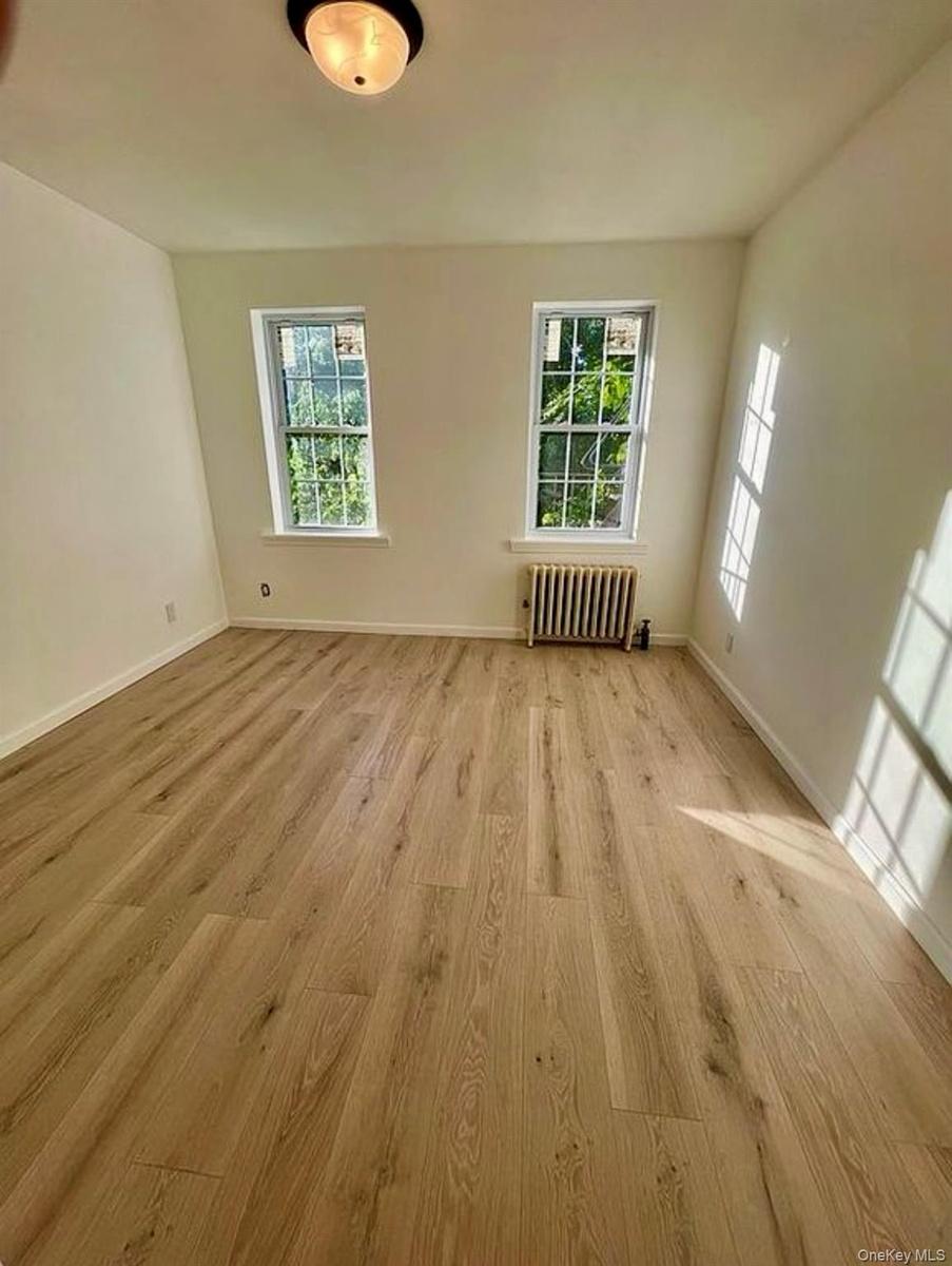 Empty room featuring radiator and light wood-type flooring