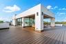 A striking rooftop-level pavilion set upon expansive wood decking, defined by clean architectural lines and floor-to-ceiling glass. Bold and contempor