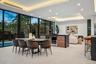 A sophisticated dining space seamlessly integrated into the open-concept design, framed by floor-to-ceiling glass and tranquil garden views. Warm wood
