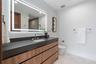 A sleek, modern bath showcasing a floating wood vanity, expansive mirror, and clean-lined contemporary finishes. Bright and minimalist, this refined s