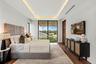 A refined modern bedroom retreat featuring custom ceiling detailing, warm wood accents, and expansive glass doors opening to lush outdoor views. Sophi
