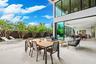 An expansive covered outdoor terrace designed for seamless entertaining, featuring a spacious dining area and comfortable lounge seating overlooking l