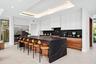 A showstopping chef’s kitchen anchored by a dramatic waterfall-edge island, rich wood cabinetry, and sleek black stone accents. Expansive and impeccab
