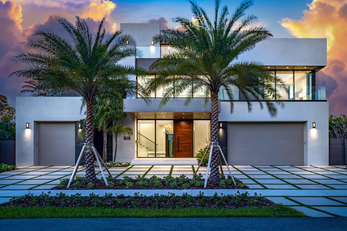 A striking modern façade framed by towering palms and clean architectural lines, illuminated beautifully at twilight. Sleek and sophisticated, this re