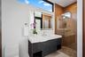 A sleek contemporary bath featuring a floating vanity with bold stone countertop, designer fixtures, and warm accent tones. Clean lines and modern fin