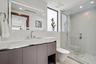 A sleek contemporary bath featuring a streamlined floating vanity, expansive mirror, and crisp white finishes accented by warm wood tones. Clean, brig