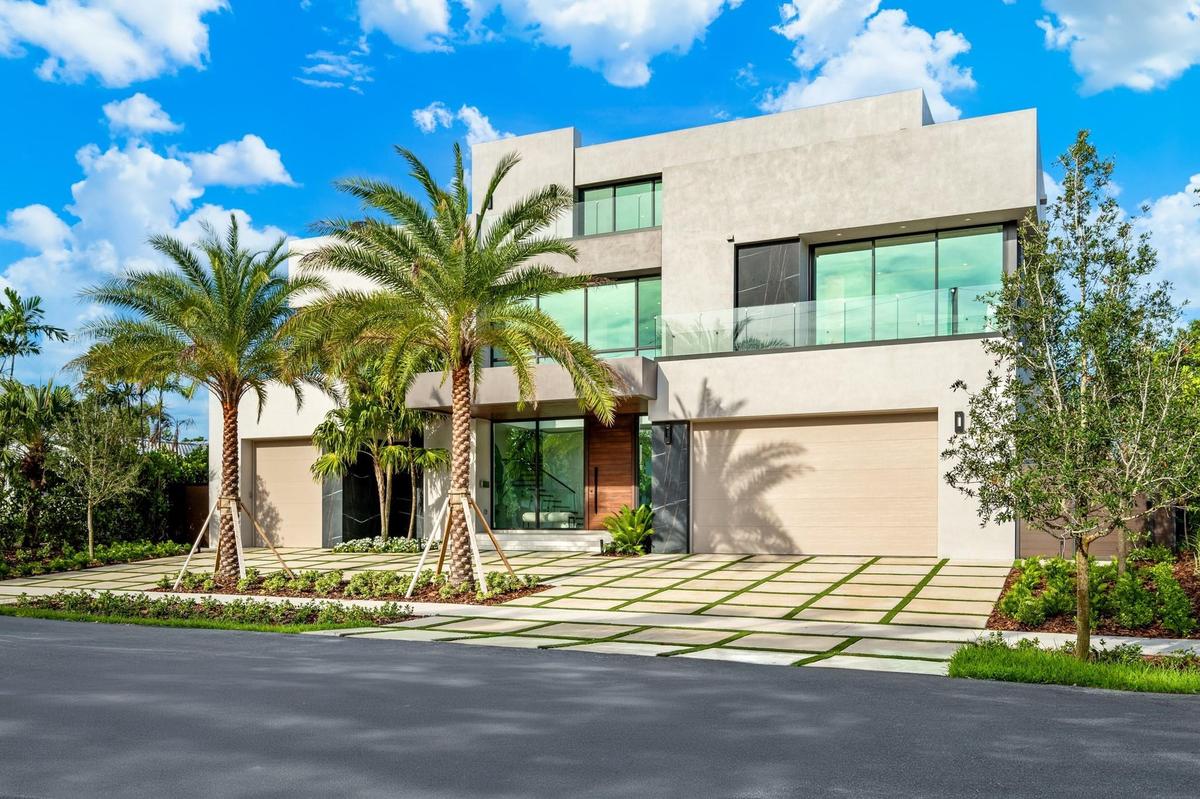 A bold contemporary exterior defined by crisp geometric lines, expansive glass, and a striking flat-roof profile framed by mature palms. Clean, modern