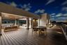 A dramatic evening terrace showcasing expansive decking, warm ambient lighting, and multiple lounge areas designed for effortless entertaining. Elevat