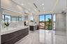 An expansive, light-filled bath retreat featuring dual floating vanities, a sleek glass-enclosed shower, and refined contemporary finishes throughout.