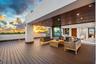 An expansive covered terrace featuring warm wood ceilings, elegant lounge seating, and seamless flow to the open-air deck beyond. Framed by breathtaki