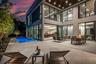 A breathtaking glass-wrapped courtyard illuminated at twilight, where soaring ceilings and expansive windows create a seamless indoor-outdoor experien