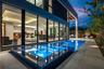 A dramatic evening poolscape framed by floor-to-ceiling glass walls that dissolve the boundary between indoors and out. Sleek, modern, and illuminated