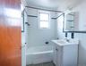 Bathroom featuring tiled shower / bath, vanity, and tile walls