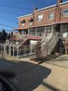 View of property featuring stairway, fence, brick siding, and a chimney