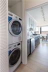 Laundry area with stacked washing maching and dryer, laundry area, a sink, and rail lighting