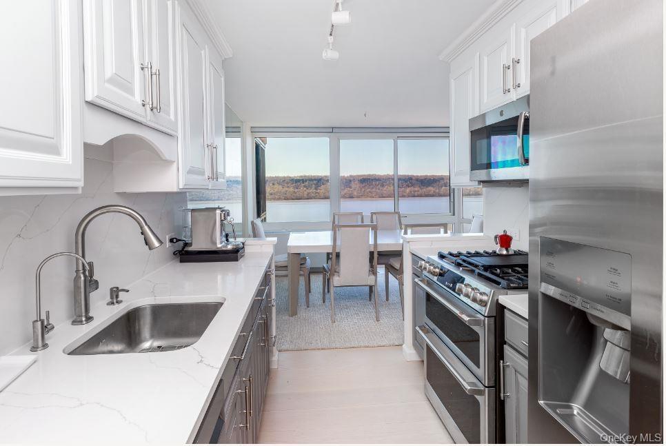 Kitchen with stainless steel appliances, white cabinets, a sink, and decorative backsplash