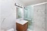 Bathroom featuring a marble finish shower, tile walls, toilet, and vanity