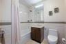 Bathroom with tile walls, a wainscoted wall, vanity, shower / tub combo with curtain, and light tile patterned floors