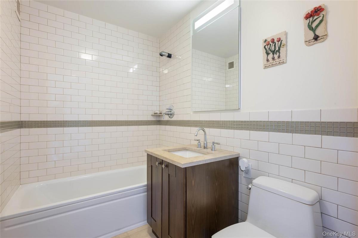Bathroom with tile walls, vanity, and washtub / shower combination