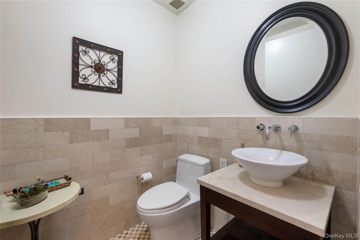 Half bath with a wainscoted wall, tile walls, and vanity