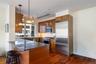 Kitchen with dark stone counters, high end appliances, backsplash, wood finish cabinetry, and decorative light fixtures