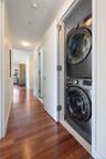 Laundry area with stacked washer and clothes dryer and dark wood finished floors