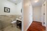 Half bath featuring tile walls, a wainscoted wall, vanity, and wood finished floors