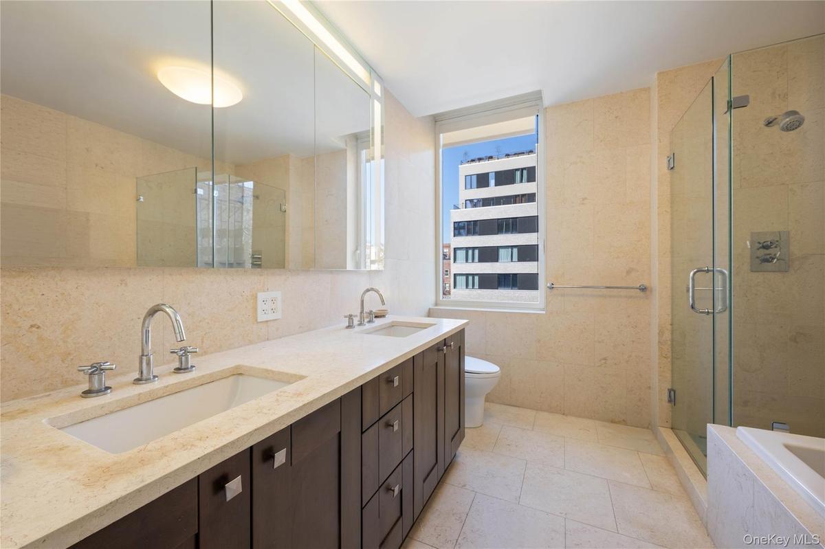 Full bathroom with double vanity, a shower stall, a bath, tasteful backsplash, and tile walls