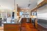 Kitchen with high end appliances, dark stone countertops, wood finish cabinets, and a peninsula