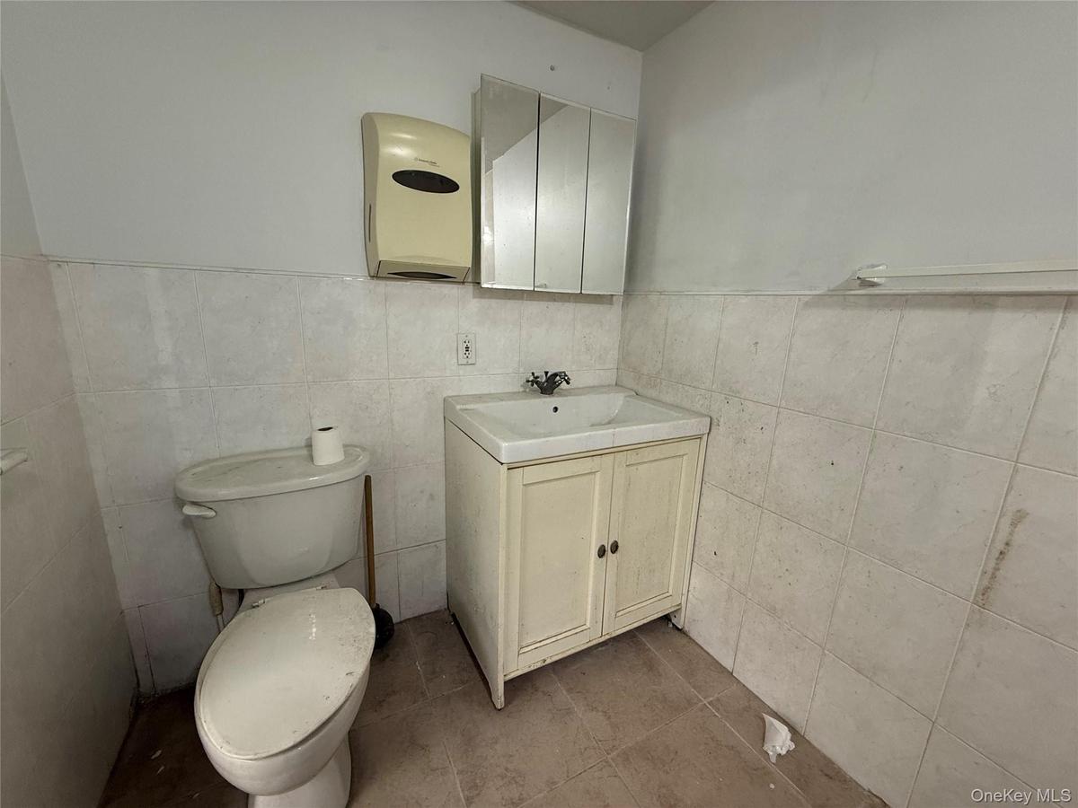 Bathroom with tile patterned flooring, vanity, toilet, and tile walls