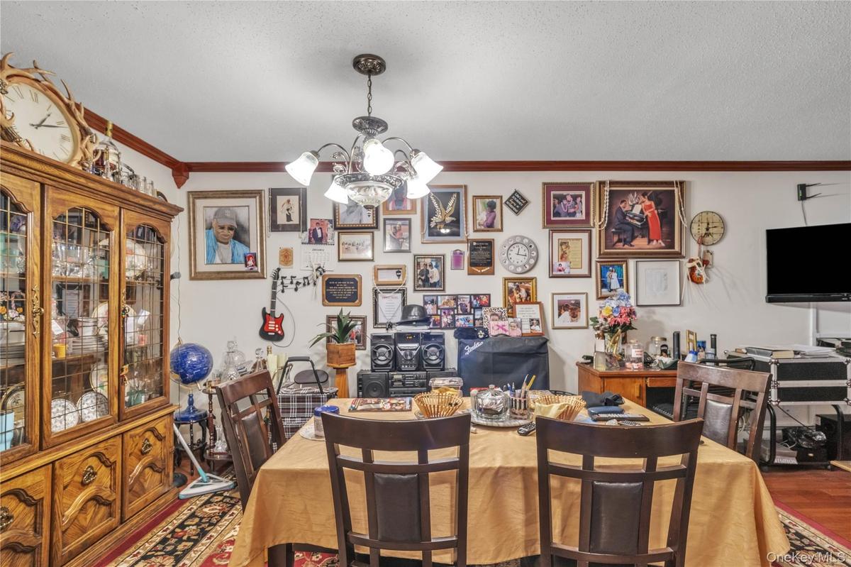 Dining space with a chandelier, crown molding, a textured ceiling, and wood finished floors