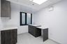 Kitchen featuring a paneled ceiling, light tile patterned floors, modern cabinets, light stone countertops, and dark brown cabinetry