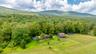 Overview of rural landscape featuring a heavily wooded area and a mountainous background