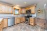 Kitchen with stainless steel appliances, a sink, light brown cabinetry, light countertops, and wallpapered walls