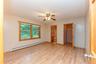 Unfurnished bedroom featuring baseboard heating, light wood-style floors, a closet, a spacious closet, and ensuite bath