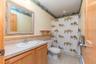 Full bath featuring a baseboard heating unit, toilet, vanity, curtained shower, and tile patterned flooring