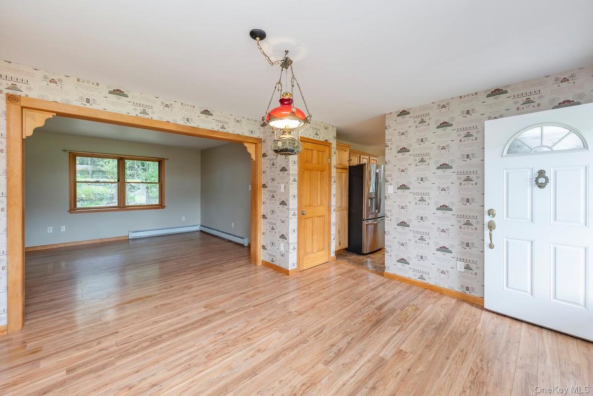 Entrance foyer featuring wallpapered walls, baseboards, light wood-style floors, a baseboard radiator, and a baseboard heating unit