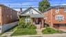 Bungalow-style house featuring roof with shingles, covered porch, a chimney, brick siding, and a front yard