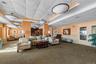 Spacious common area featuring patterned carpet flooring, recessed and flush-mount lighting, decorative wall paneling, and a dual-pane glass door