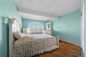 Spacious room featuring wood-finish flooring, light blue wall paint, a broad window with horizontal blinds, and a built-in sliding panel closet