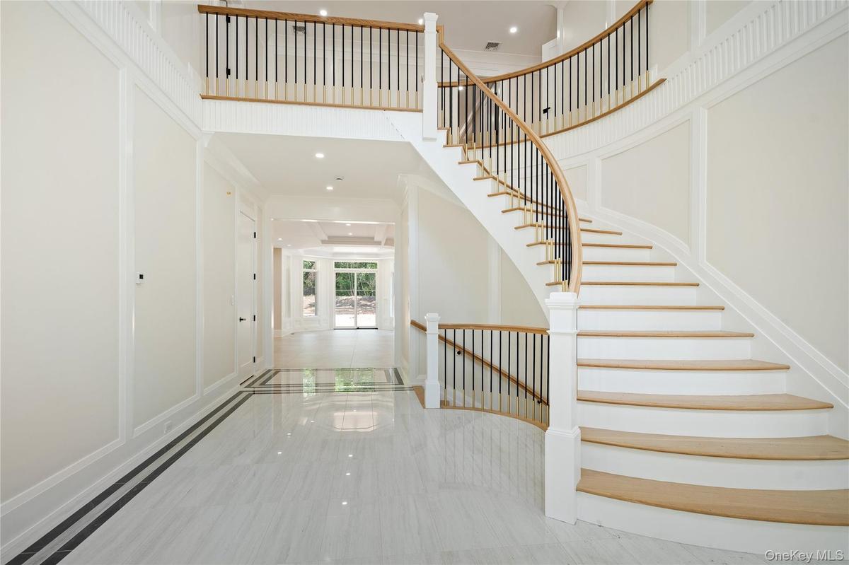 Foyer entrance with a towering ceiling, recessed lighting, stairs, marble tiled flooring, and inlaid floor details