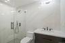 Bathroom with vanity, a marble finish shower, and tile walls