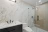 Full bathroom featuring vanity, a marble finish shower, tile walls, recessed lighting, and stone wall