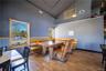 Dining space featuring high vaulted ceiling, wood finished floors, and a wainscoted wall