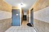 Corridor with tile patterned floors, tile walls, baseboard heating, and elevator
