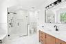 Full bathroom featuring vanity, a marble finish shower, tile walls, light marble finish flooring, and wainscoting