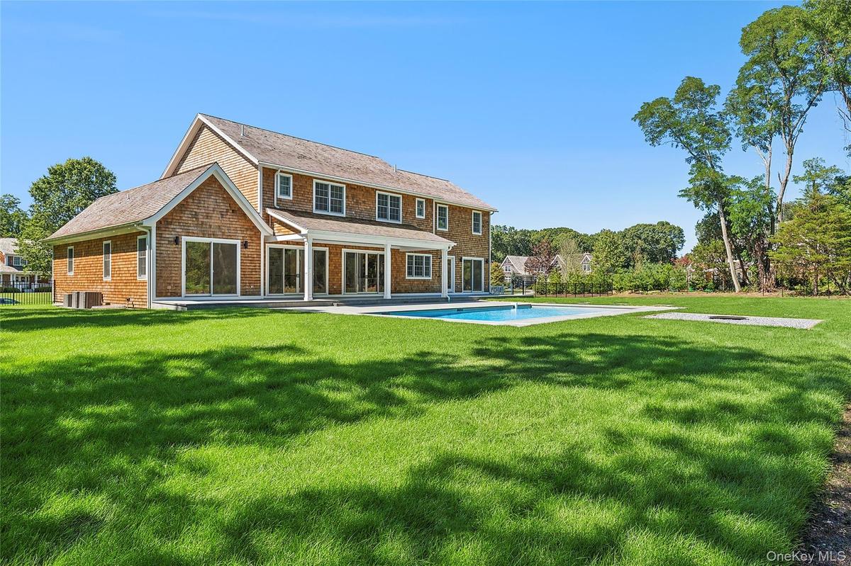 Rear view of house with a patio, an outdoor pool, and a yard