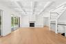 Unfurnished living room with beamed ceiling, coffered ceiling, light wood-style flooring, a fireplace, and a decorative wall