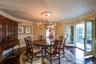 Dining space featuring dark wood-style flooring, wallpapered walls, a chandelier, and ornamental molding