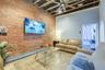 Tiled living room featuring a ceiling fan, brick wall, a high ceiling, beamed ceiling, and baseboard heating